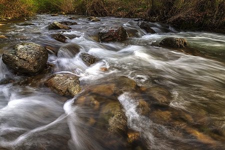 用石头在河中流动的水的美丽运动模糊视图