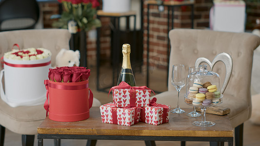 香槟玫瑰花摄影照片_浪漫的情人节豪华布置，咖啡桌上配有礼盒香槟和马卡龙