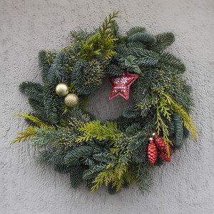 冷杉树枝的圣诞花环，房子的灰色墙上挂着装饰、星星、球
