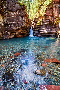 瀑布穿过陡峭的悬崖，进入带有彩色岩石的原始蓝色海水