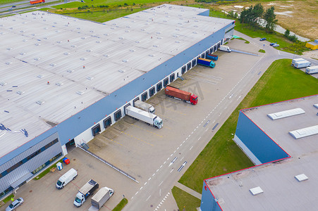 货车仓库摄影照片_工业仓库装卸码头的空中拍摄，许多卡车与半拖车装载商品。