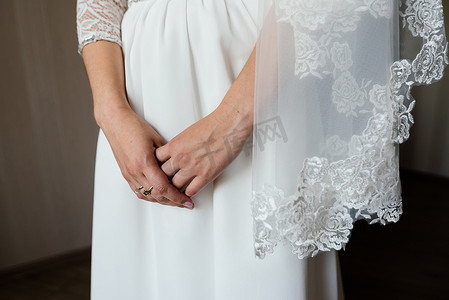 新娘的双手交叉在白色礼服上