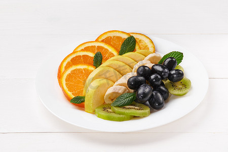 切片水果摄影照片_板上的橙子、香蕉、猕猴桃、苹果和葡萄片