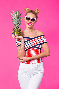 粉红色背景中戴墨镜和菠萝的时尚肖像女性