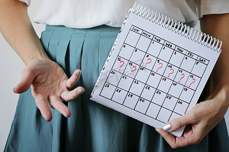 rili日历摄影照片_女人拿着日历，明显错过了月经。