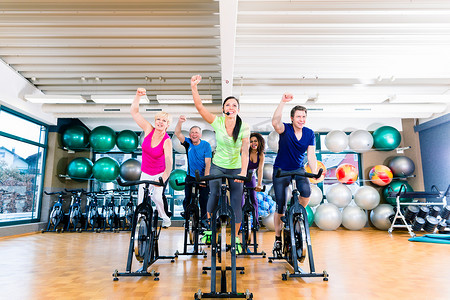 培训课程摄影照片_一群男人和女人在健身房骑健身自行车