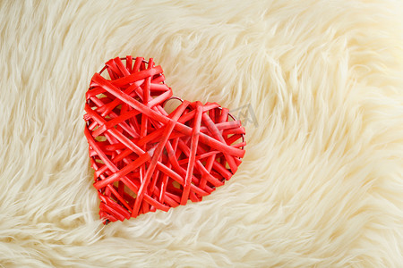 一颗柳条红色的心躺在我们的白色羊毛毯子里。