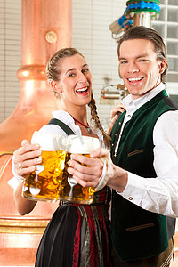 发酵罐摄影照片_啤酒厂里拿着啤酒杯的男人和女人