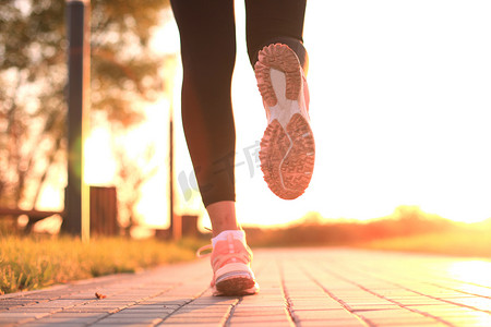 在日落或日出时在户外的鞋子特写镜头上跑步的脚。