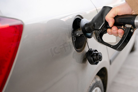 随着燃油成本上涨，一名男子在加油站附近用柴油为他的汽车油箱加油