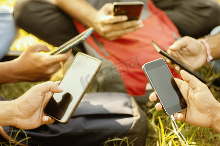 沉迷手机摄影照片_有选择地关注手，年轻人手持手机的特写-大学生沉迷于智能手机-年轻的千禧一代忙于手机-一群朋友在社交媒体上分享内容。