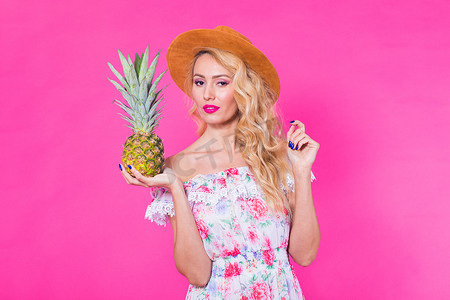 粉红色背景中带菠萝的年轻美女时尚肖像