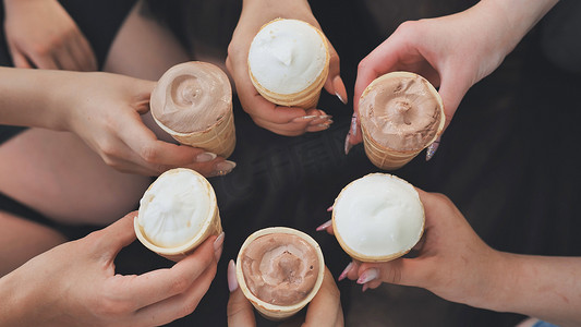 女朋友们围成一圈，用华夫饼杯中的冰淇淋手牵手。