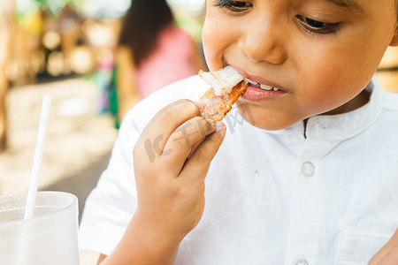 拉丁男孩在一家传统的中美洲餐厅里咬一块chicharron