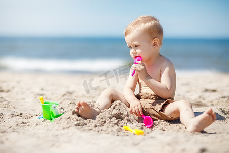 玩沙子摄影照片_孩子在沙滩上玩沙子。