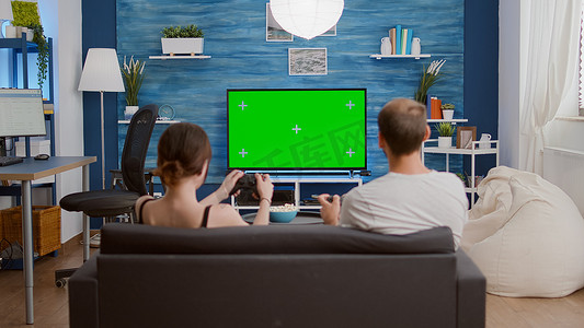年轻女子和男友在绿屏上玩在线游戏的静态三脚架照片
