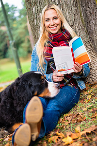 秋季公园里带着狗看书的女人