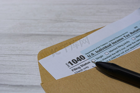 个人所得税摄影照片_纳税表格 1040。美国个人所得税申报表，装在桌子上的棕色信封中。