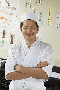 餐厅里一位快乐的亚洲厨师双臂交叉站立的肖像