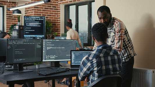 软件开发人员在查看多个屏幕的笔记本电脑和计算机键盘上编写代码