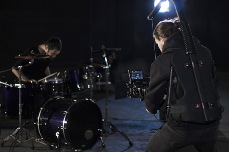专业摄影师拿着安装在简易装备上的相机并拍摄鼓手。