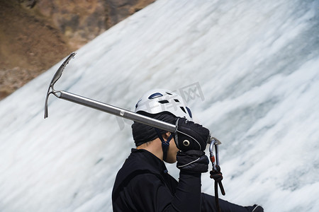 一名男子拿着冰斧在冰川上攀爬。