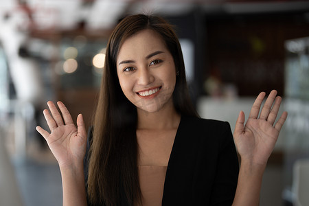 博客摄影照片_微笑的亚洲女人挥手看着相机，她制作视频博客或在家打电话，快乐友好的视频博主。