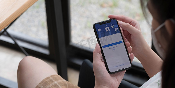 泰国清迈，2021 年 11 月 14 日：手持 iPhone X 的女性在屏幕上使用社交互联网服务 Facebook。