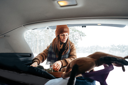 年轻女子在冬季旅行时从车里拿行李
