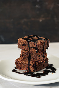 一堆巧克力核仁巧克力饼和巧克力酱放在大理石桌上的白盘子上。