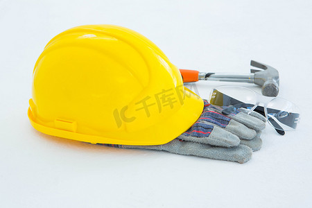 佩戴安全帽摄影照片_有锤子、眼镜和黄色安全帽的防护手套