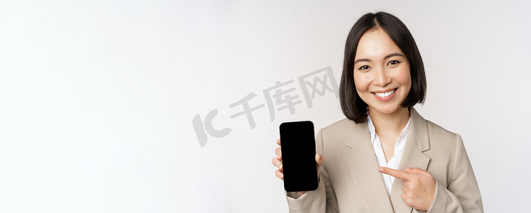 小程序界面摄影照片_显示智能手机应用程序界面、手机屏幕、站在白色背景上的亚洲企业女性肖像