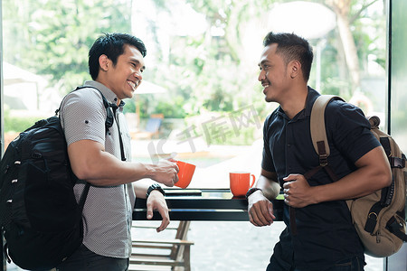 两个快乐的年轻人聊天和喝咖啡的侧视图