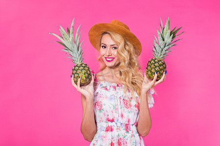 粉红色背景中带菠萝的年轻美女时尚肖像
