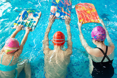 一群男孩和女孩在教练的指导下在游泳池里训练和学习游泳。