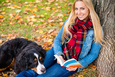 秋天公园里带着狗看书的女人