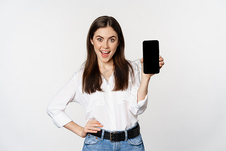 微笑的女人展示智能手机应用程序界面、手机屏幕、展示促销优惠、站在白色背景上