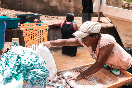 在北加勒比贫困社区的一条河里洗衣服的贫穷黑人妇女