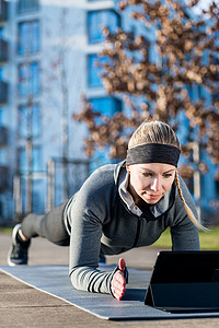 励志健身摄影照片_在户外锻炼时观看励志视频的年轻女性