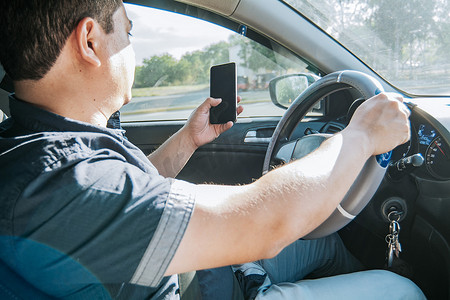 拿着手机的人，另一只手拿着方向盘，开车时用手机的人，不负责任驾驶的概念，开车时用手机分心的司机