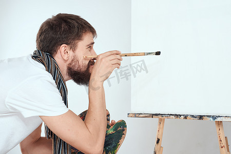 男性艺术家在画架调色板艺术创意浅色背景上作画