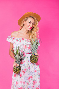 粉色菠萝摄影照片_幸福的女人和菠萝在粉红色背景下的画像。
