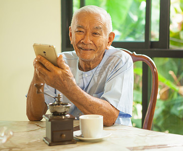 快乐的亚洲老人在家使用手机