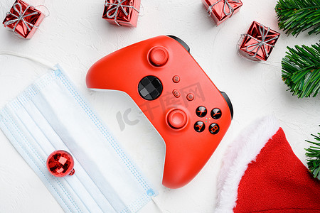 圣诞树玩具中的红色游戏手柄，带有covid面具，白色石桌背景，顶视图平躺