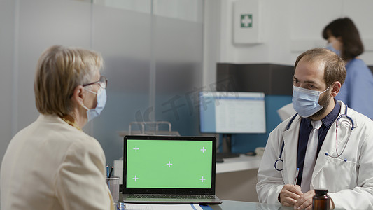 退休妇女和医生用绿屏分析笔记本电脑