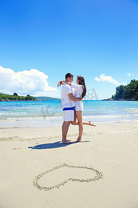 恋爱中的浪漫情侣在沙滩上玩得开心，心画在沙滩上