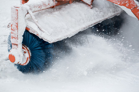 城市服务清雪，一辆带旋转刷的小型拖拉机在冬日清扫城市公园的一条道路，清除刚落下的雪。