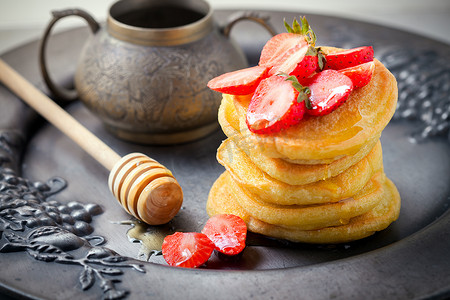 蛋糕蜂蜜摄影照片_堆甜薄煎饼用草莓和蜂蜜。