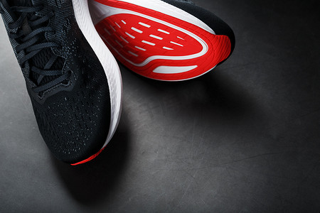 新潮摄影照片_黑色运动鞋，黑色背景上有红色鞋底。