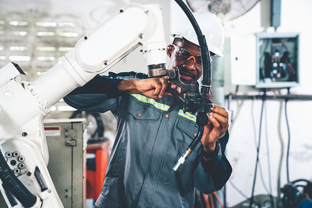 非洲裔美国工厂工人与熟练的机械臂一起工作